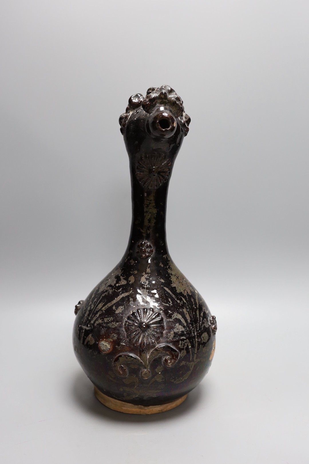 A primitive black glazed terracotta ewer with decorative headed spout and twisted handle - 38cm high